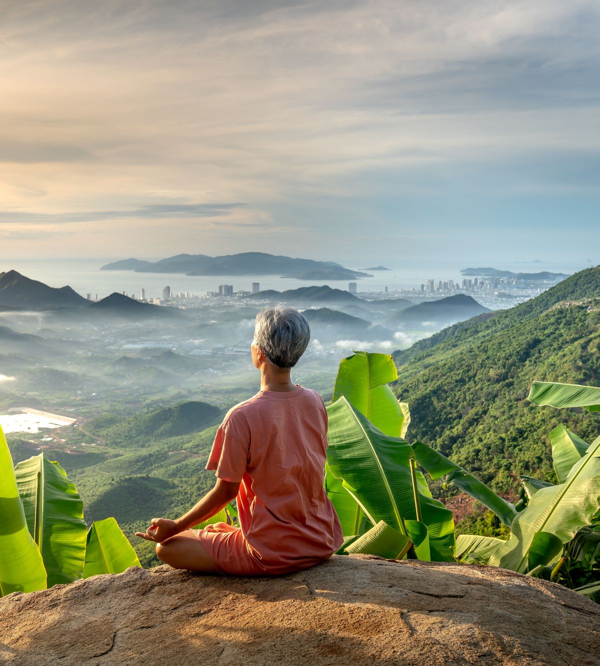 A person meditating on the beach at sunset